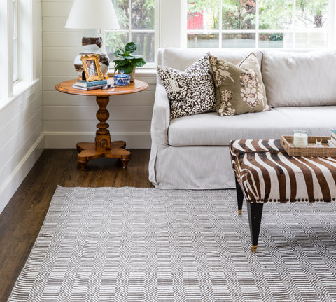 an elegant living room with a brown zebra ottomon on top of a brown and white geometric area rug.