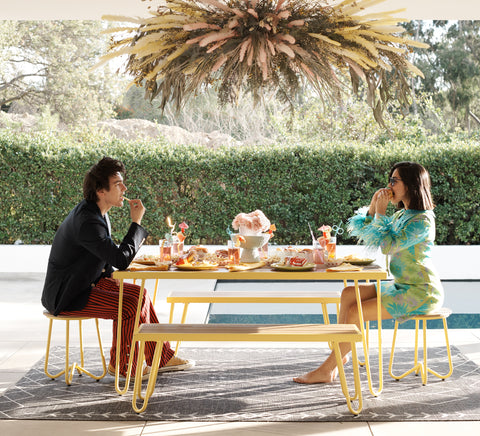 couple eating at an outdoor picnic table with modern grey rug underneath.