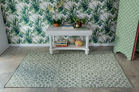 green and white area rug infront of a palm tree wall papered wall.