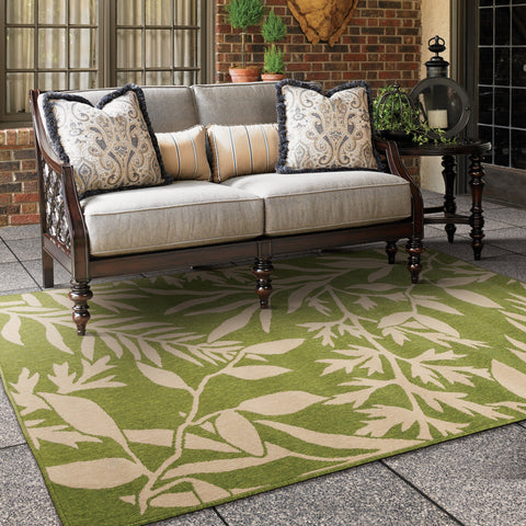 green outdoor area rug with palm leaves under an outdoor tommy bahama love seat
