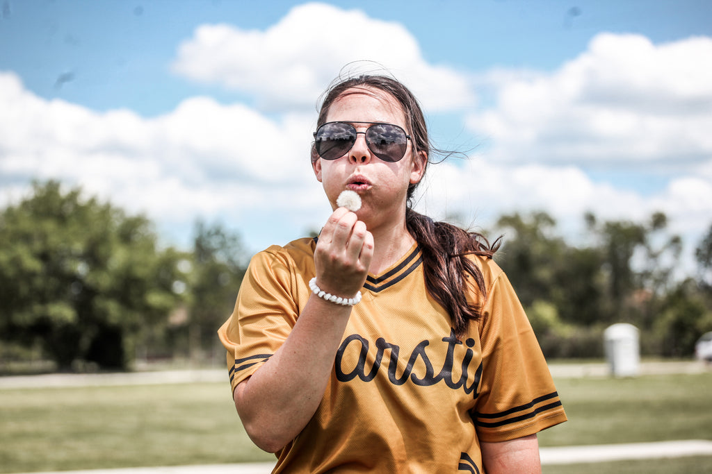 Tori Kinsler of the Warstic Woodmen blowing on a dandelion.