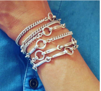 Ladies arm showing a solid silver equestrian inpired bit long necklace wrapped around qrist as a bracelet