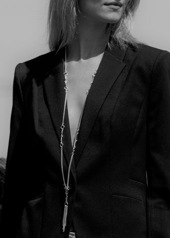 black and white shot of model wearing silver equestrian inspired neckchain with tassel