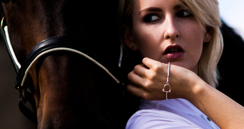 Blonde model wearing silver equestrian styled bangles next to a horse