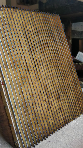 A close-up shot of brass printing block with straight lines, kept on a table.