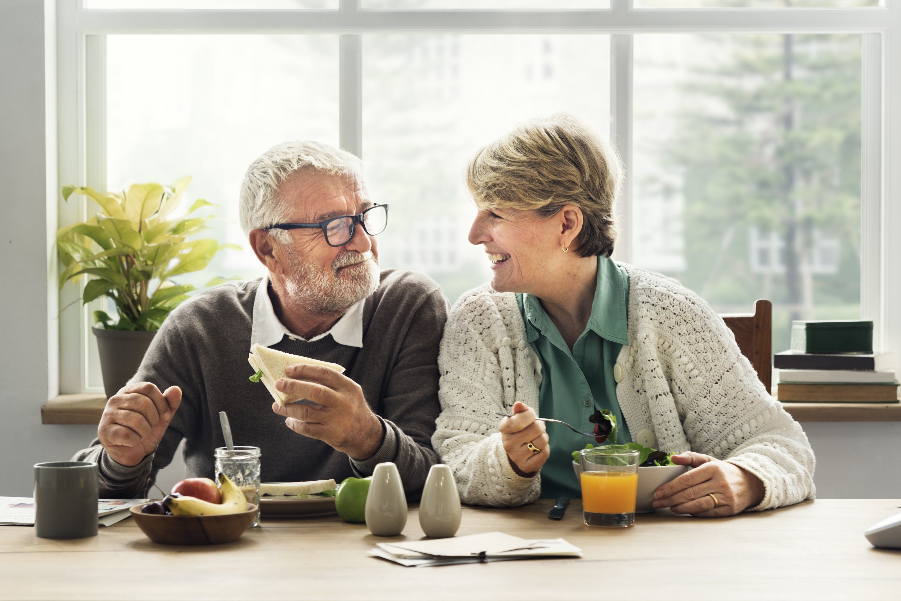 older couple smiling at each other while eating breakfast