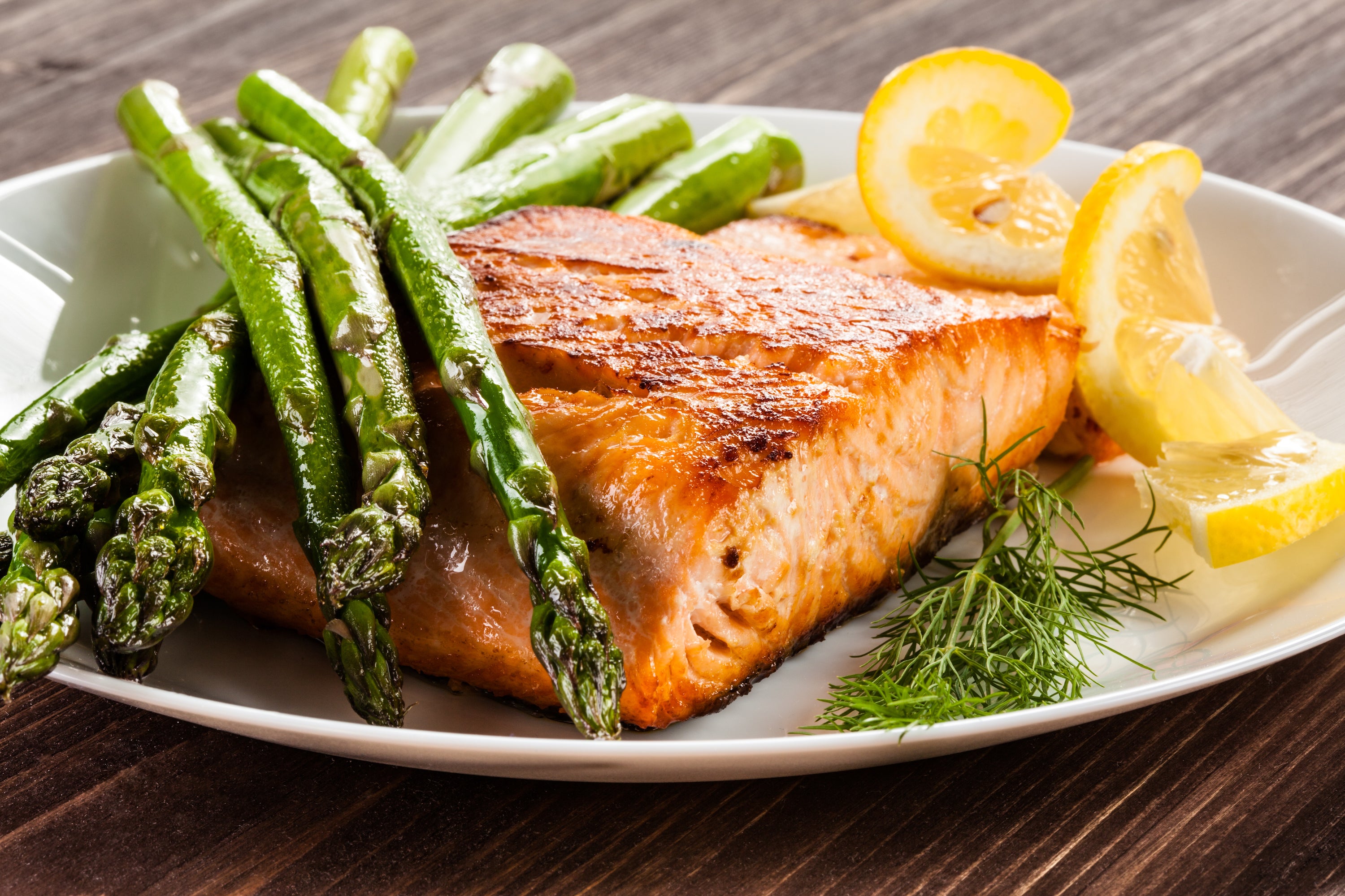 grilled salmon on plate with asparagus and lemon garnish