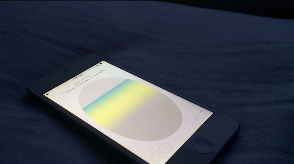 An Iphone rests on a surface with the flight simulator app open, depicting an airplane window. The iPhone reads that the time remaining on the "trip" is 7 hours, 14 minutes, and 42 seconds.
