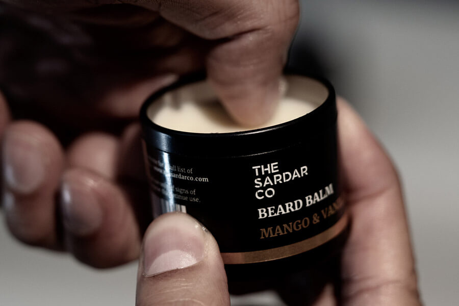 scooping beard balm out of tin