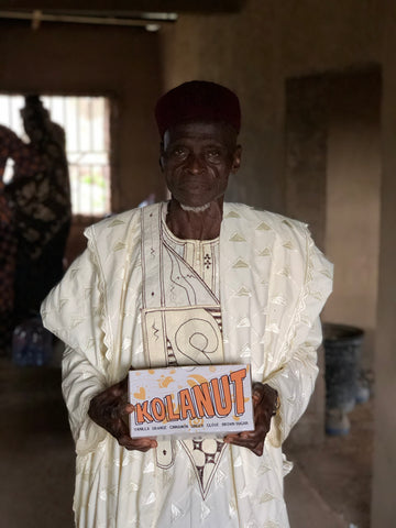 Adewale (93), Chairman of the Osun State Kolanut Association holding a box of Bissy energy drinks.
