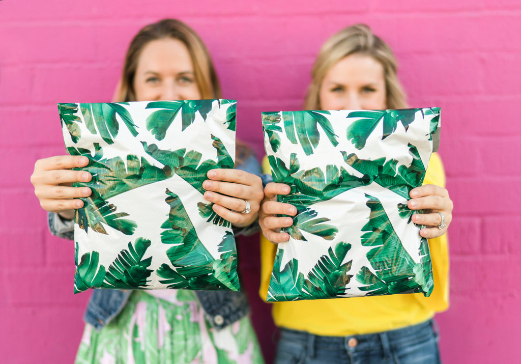 photo of kelsey and rose holding up palm print shipping bags