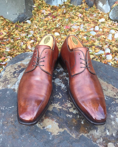 Light Brown Magnanni Colo Derby Shoes Mirror Shined on a Boulder in front of a pile of Autumn Leaves