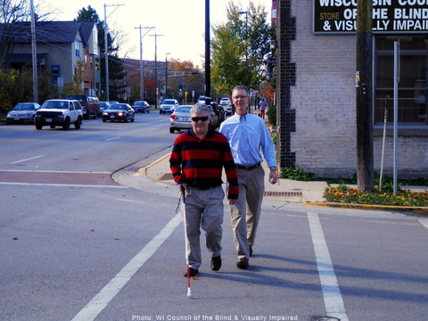 Marshall Flax crossing a street with blind person with a white cane