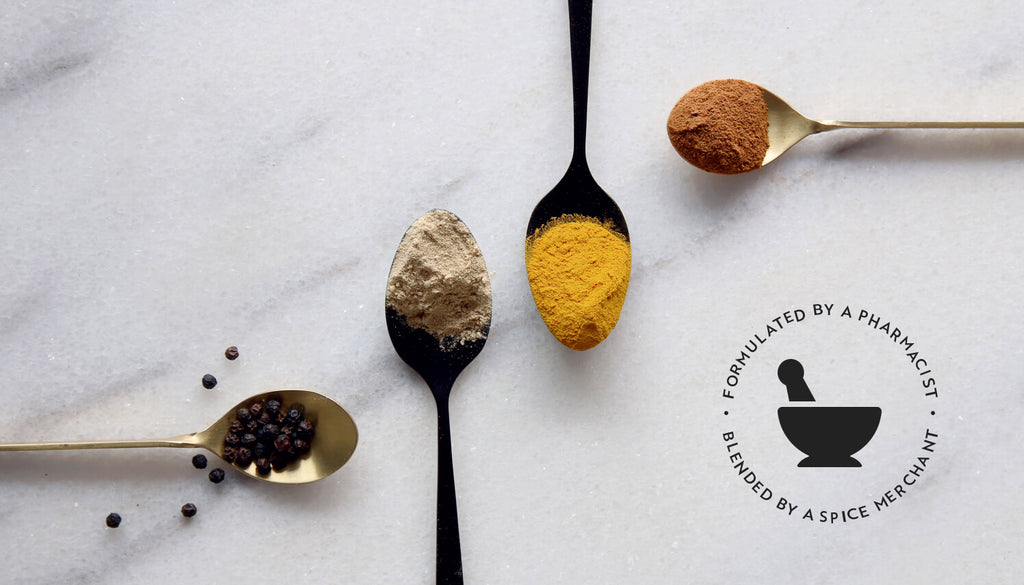 A Blend of spices turmeric, black pepper, ginger and cinnamon, displayed in spoons on a marble table.