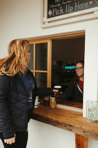 Women wearing a blue graphic t-shirt with a triangle shaped mountain illustration on the front. Black denim jeans. High Waisted. Booties. Coffee. Outdoor Coffee Shop in Leavenworth, Washington. PNW Style. Pacific Northwest.