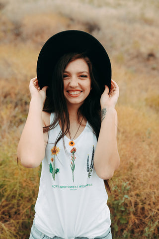 Graphic Style Tank top with Pacific Northwest Wildflowers on the front. Cute Wide Brim Hat. Field. Summer time. Golden Hour. Wearing white tank tops with jeans and jeans shorts. Summer time. Wenatchee, Washington. PNW Style. Pacific Northwest. Mountains. Mountain Style.