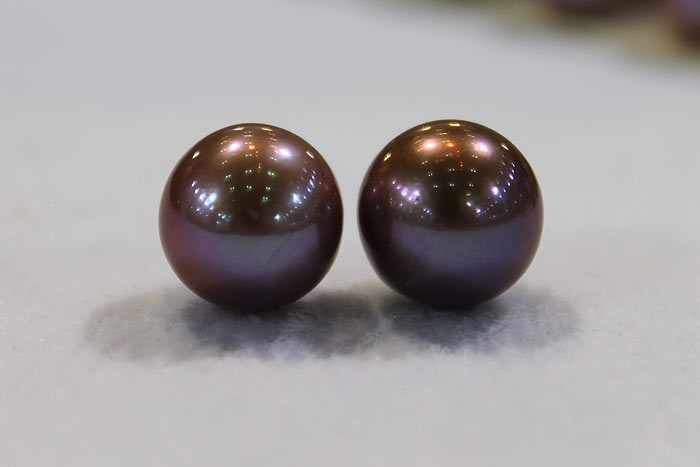 a pair of matched pearls in a deep, dark purple color