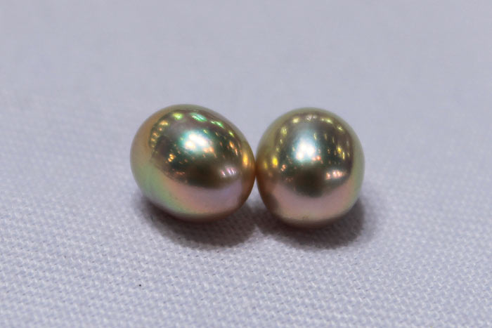 a close up of a pair of drop pearls