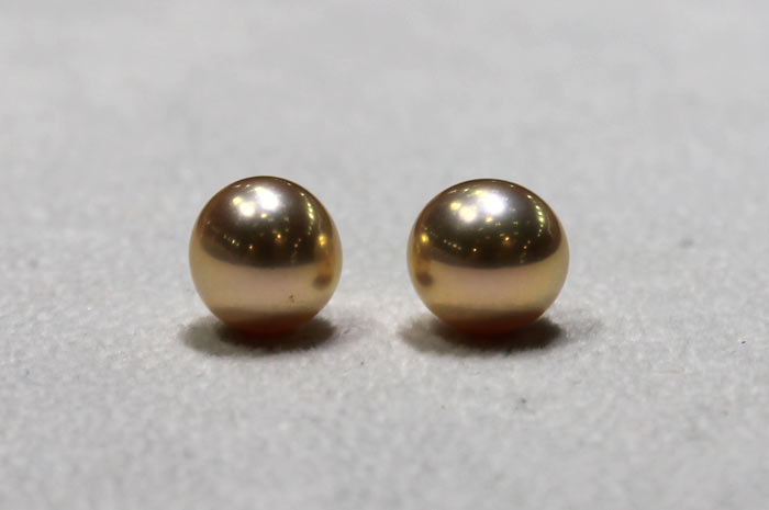 close up of a pair of golden metallic pearls