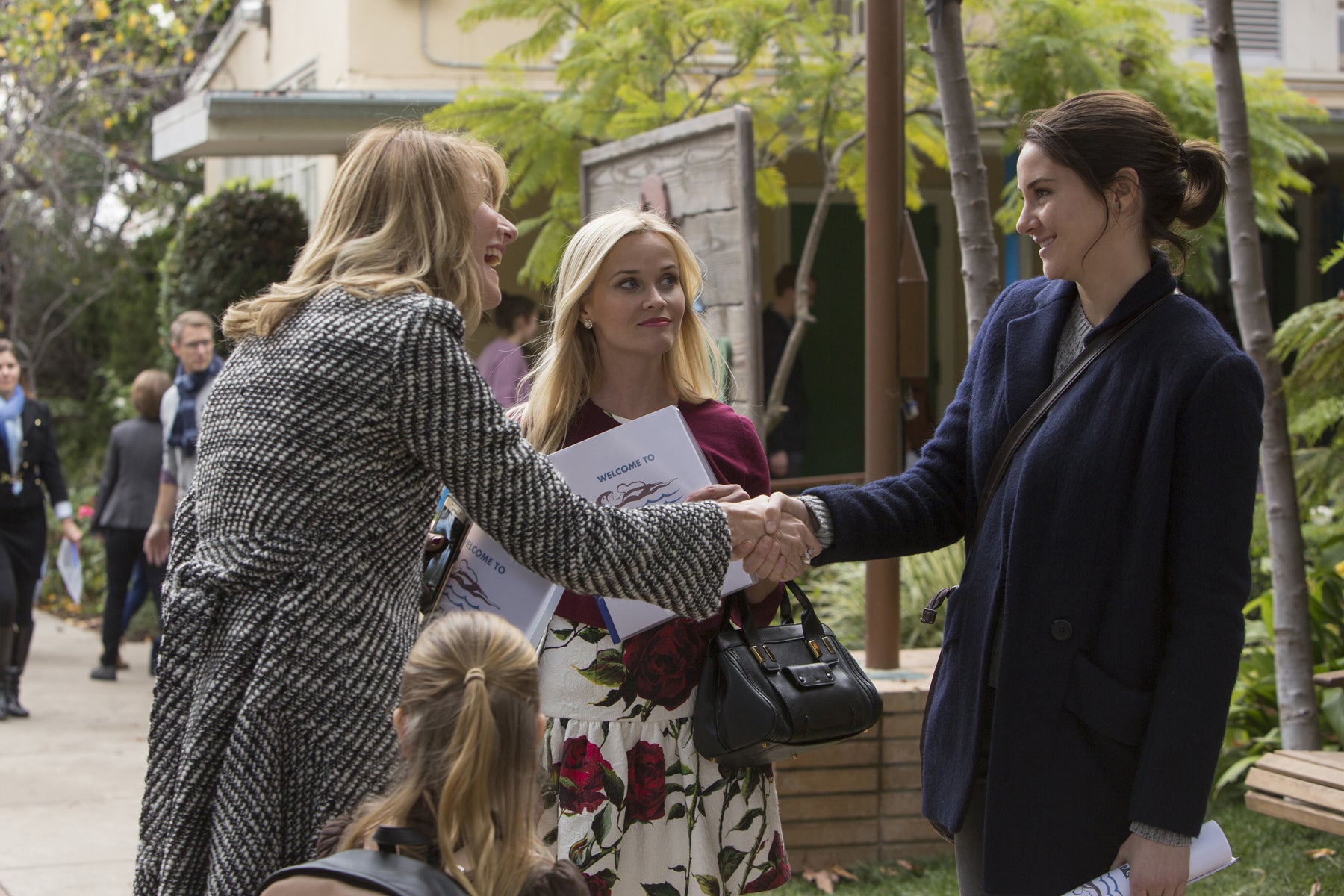 Jane Chapman (Shailene Woodley) shakes hands with Renata Klein (Laura Dern) as Madeline Martha Mackenzie (Reese) looks on.