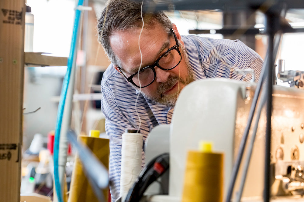 Detroit Denim founder Eric Yelsma inspects an industrial sewing machine.