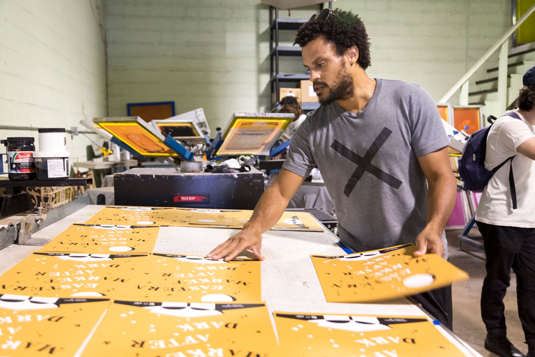 One Custom City founder Ron Watters arranges printed materials on a large table in a printing studio.