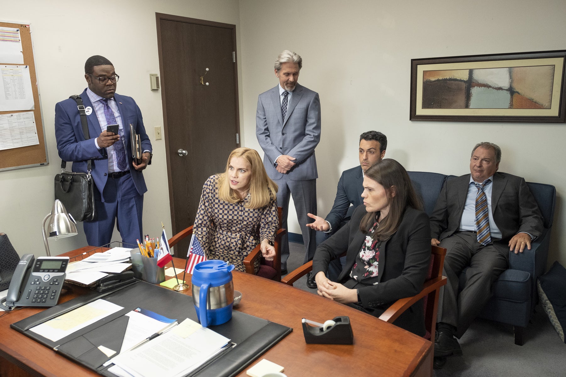 Richard, Amy, Marjorie, Kent, Dan, and Ben strategize in Selina’s office.