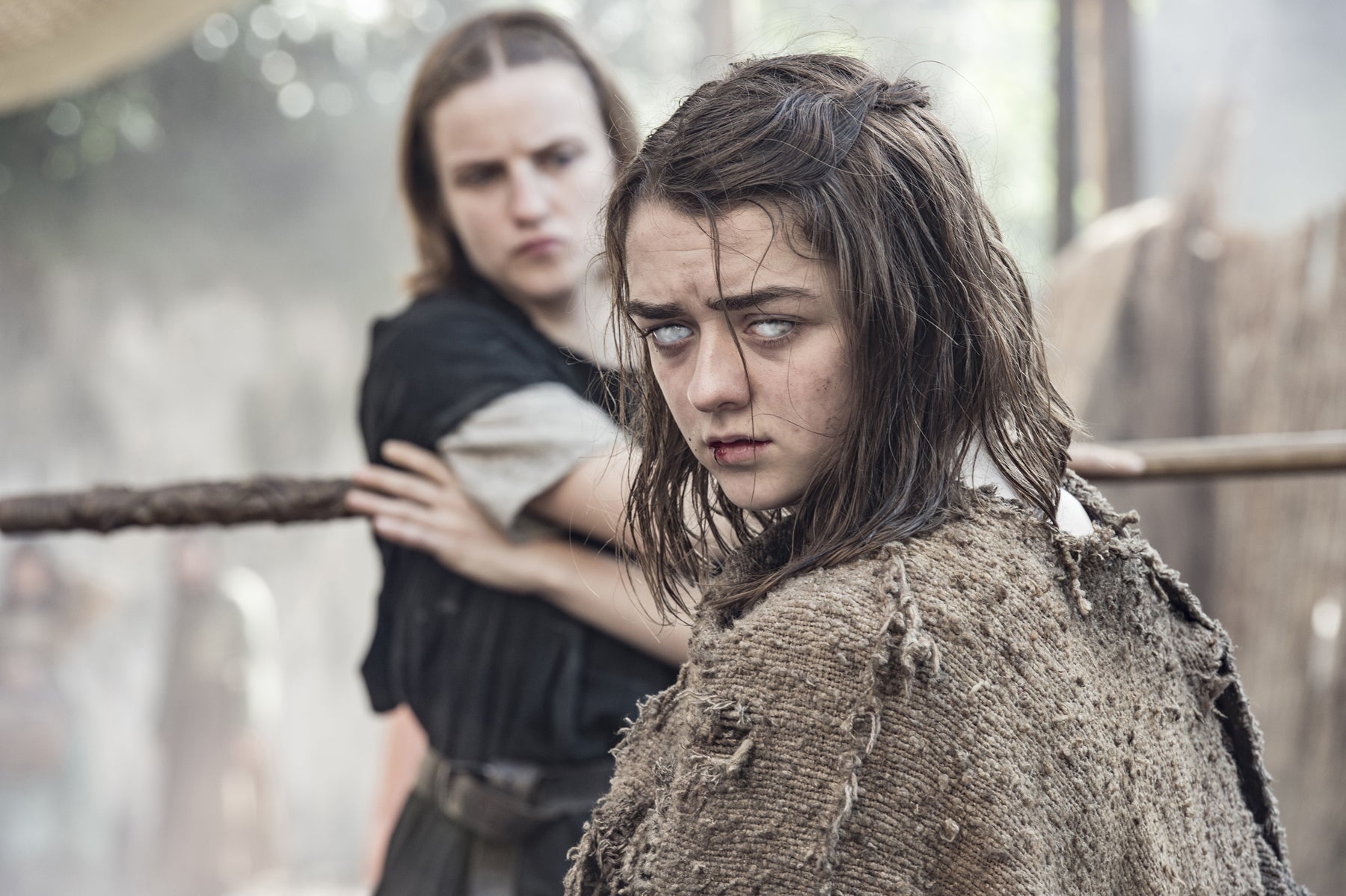 Arya Stark, blinded, stands in the foreground with the waif in the background.