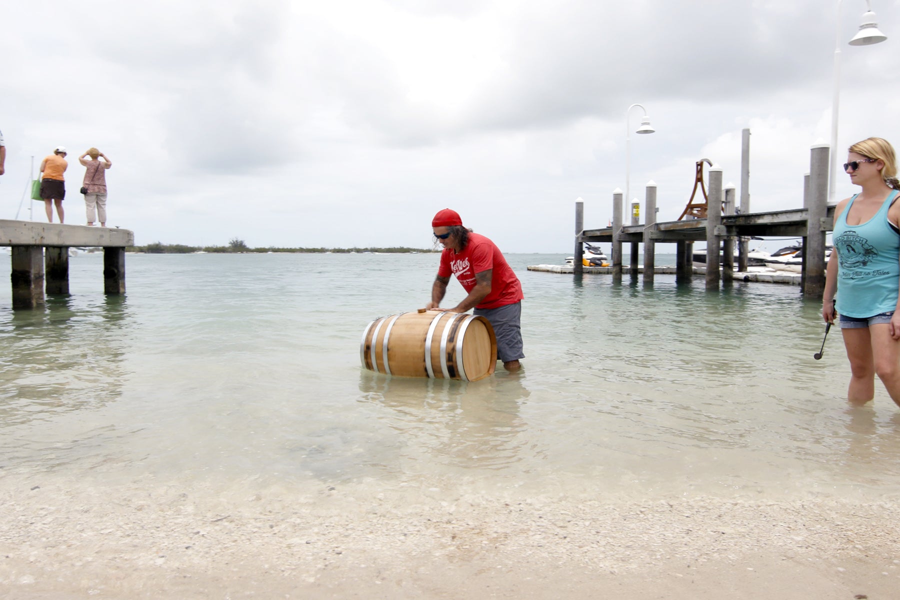 Paul Menta of Key West Legal Rum Distillery submerges a wooden barrel in the shallow salt water.