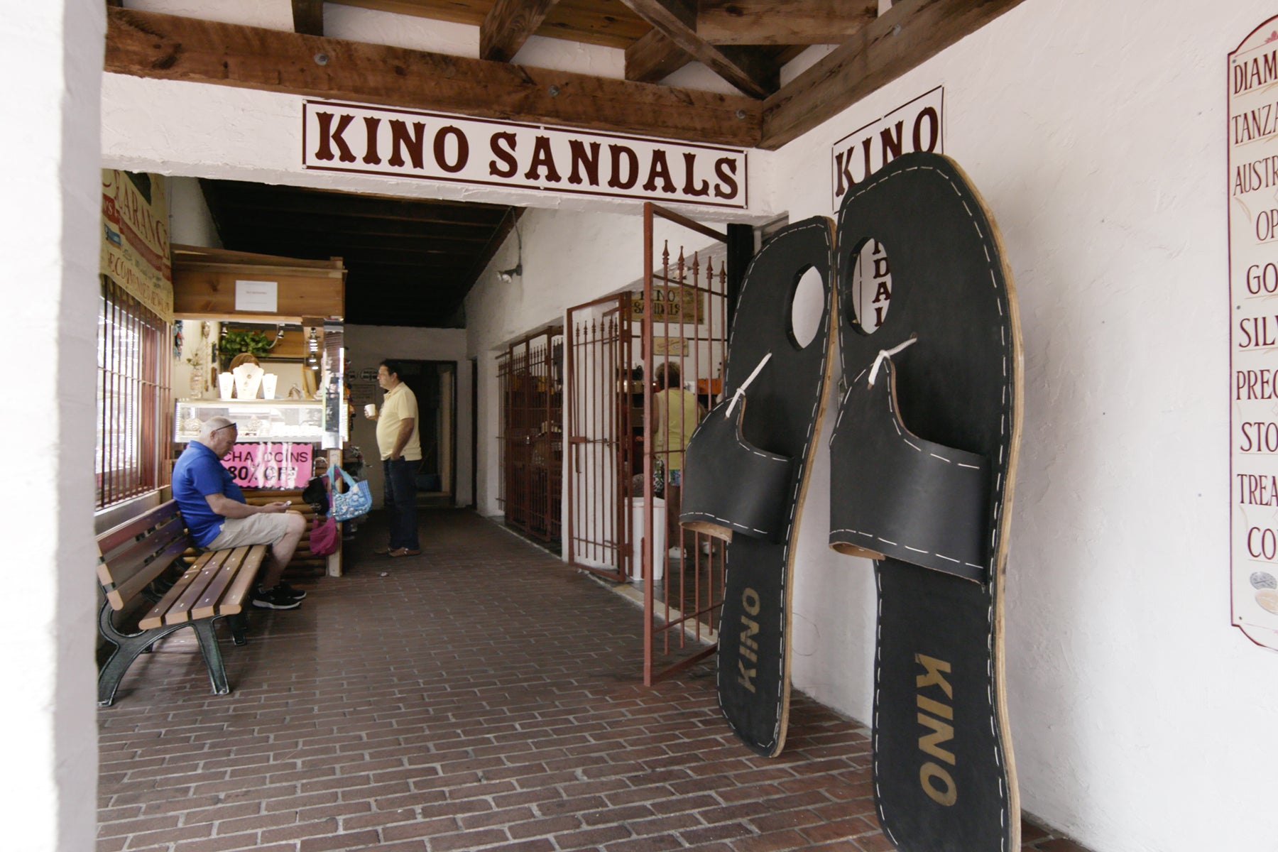 Exterior of Kino Sandals in Key West, Florida. Two oversized sandals lean on the wall by the shop's door.