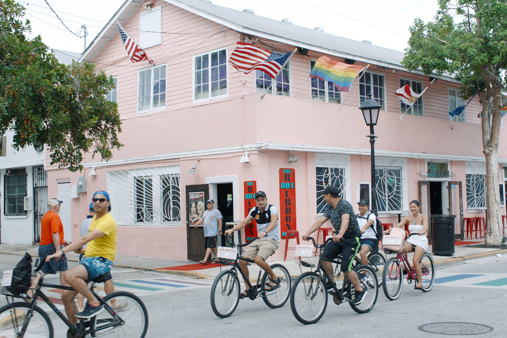A group of people cycle past a pink building in Key West, Florida