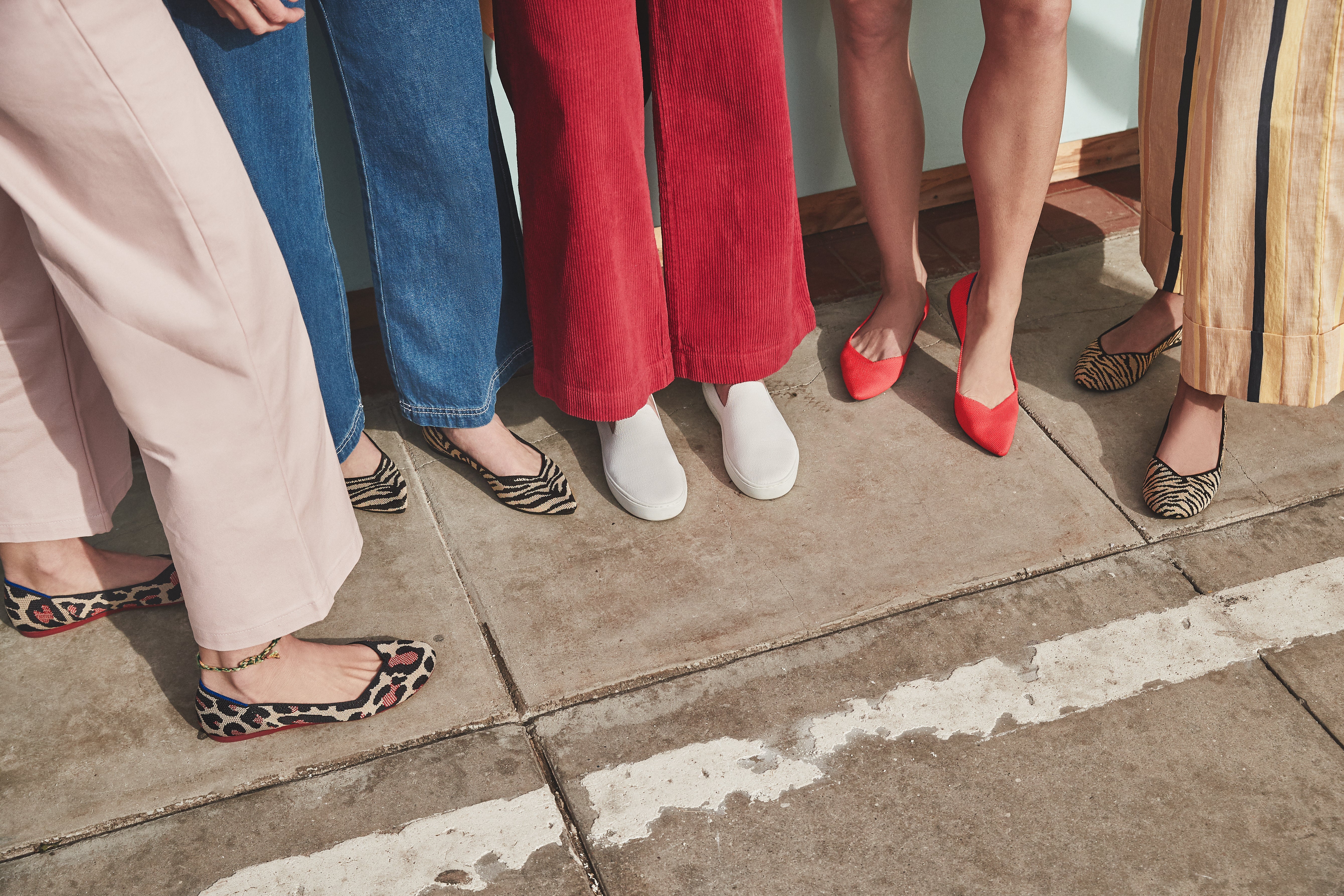 Pointed leopard print flats, pointed zebra flats, white sneakers, red pointed flats, and original flats in zebra print being modelled. 