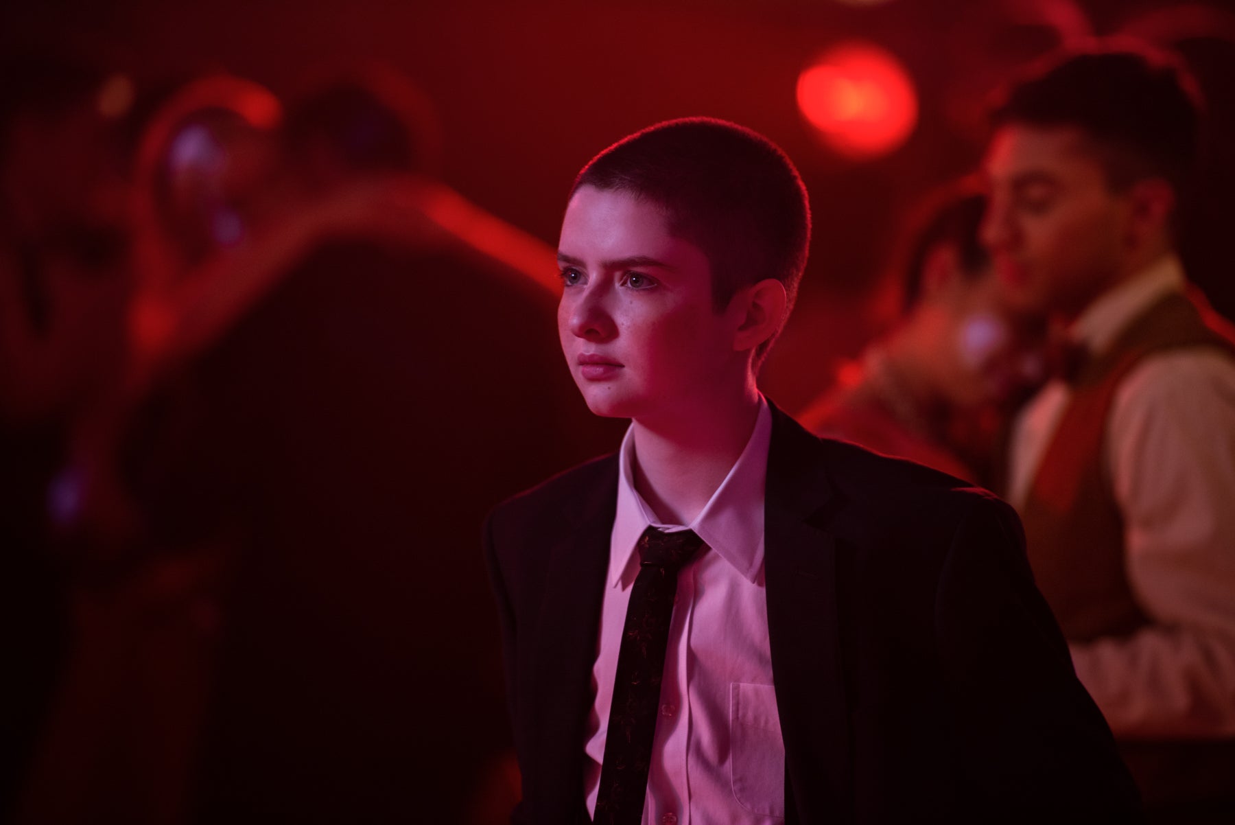 Theo, wearing a suit at the Valentine’s dance, looks off camera in a scene from Chilling Adventures of Sabrina.