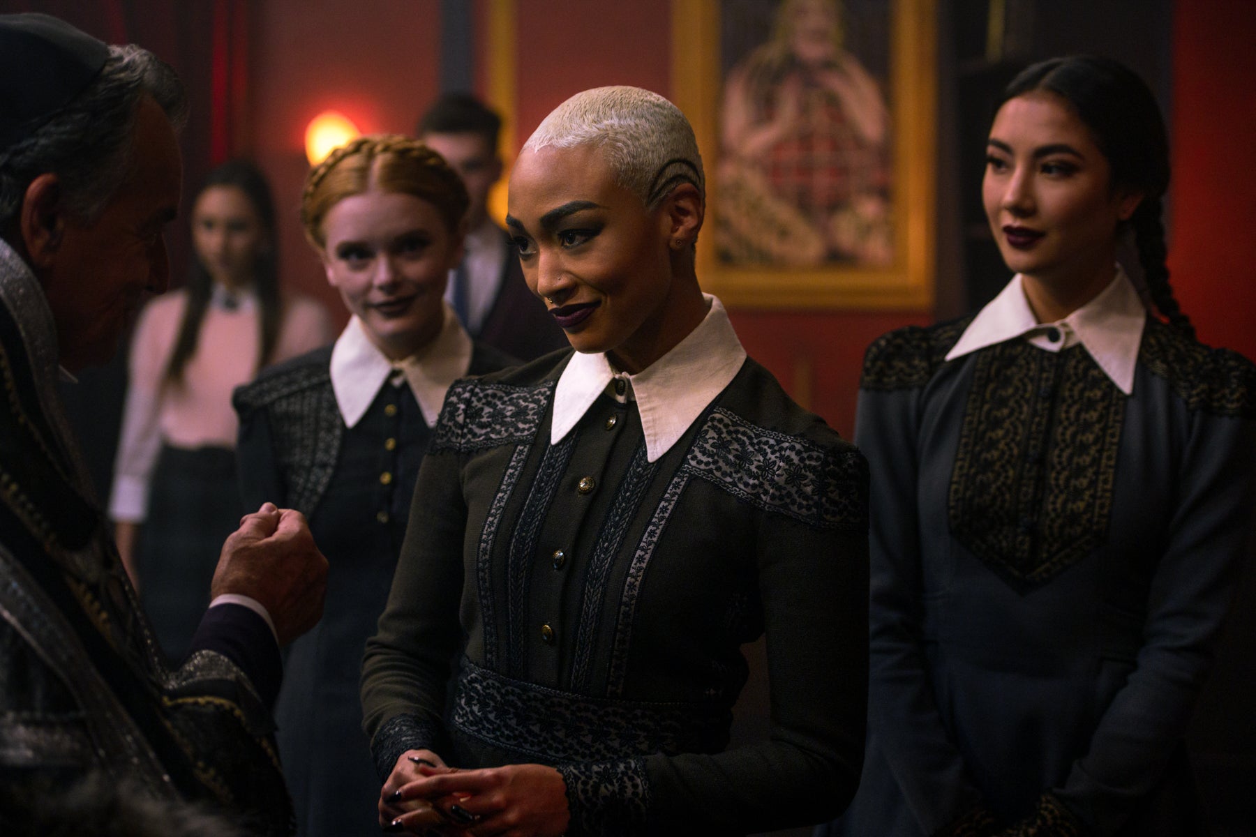 The Weird Sisters stand in a row with Prudence in the foreground, addressing a man off camera in a scene from Chilling Adventures of Sabrina.