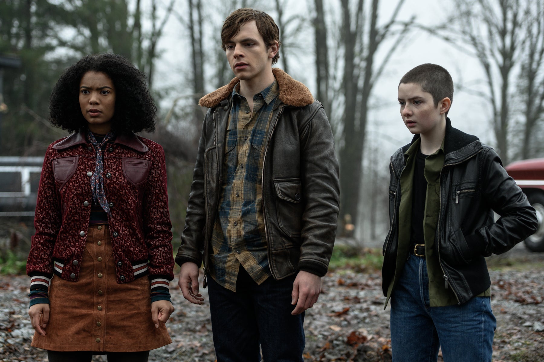 Ros, Harvey and Theo stand in a row, looking concerned at something off camera in an outdoor scene from Chilling Adventures of Sabrina.