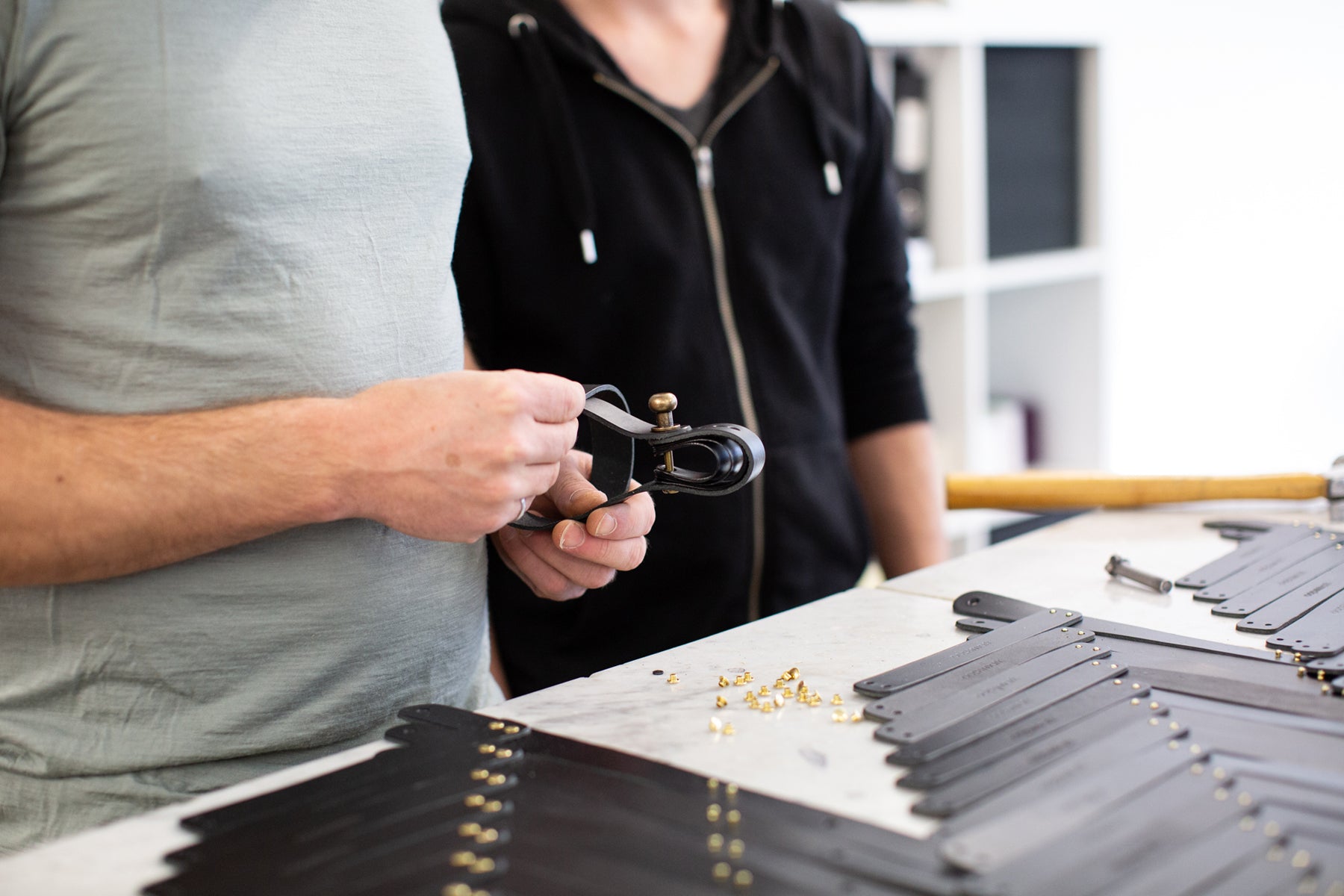 Close up of Oopsmark founder Jesse Herbert's hands, examining a series of leather straps on a tabletop.