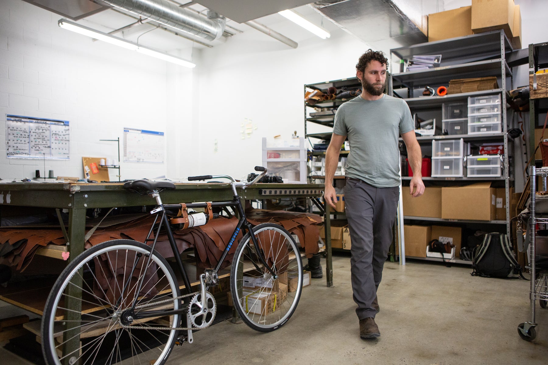 Jesse Herbert, founder of Oopsmark, walking in his studio next to his bicycle.