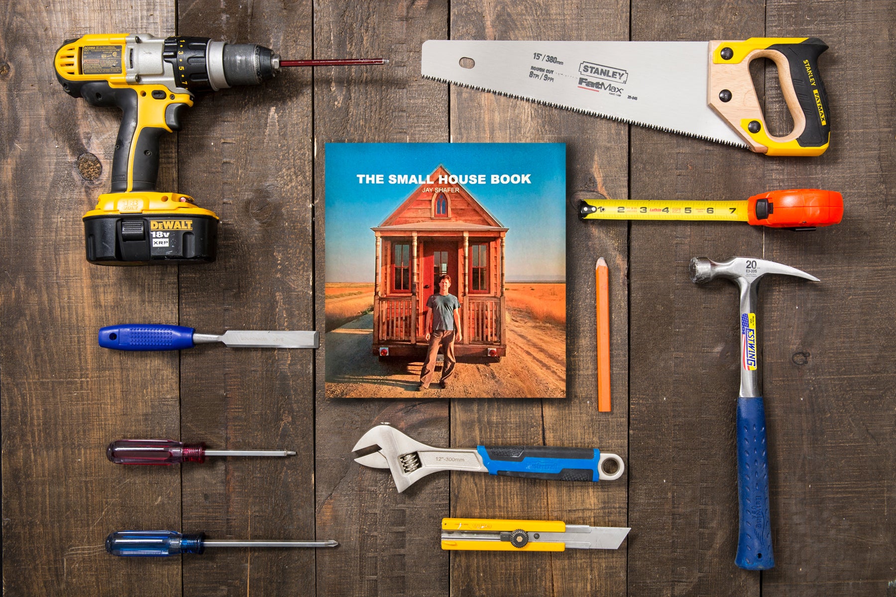 The Small House Book, by Jay Shafer, sits on a wood surface, surrounded by tools.