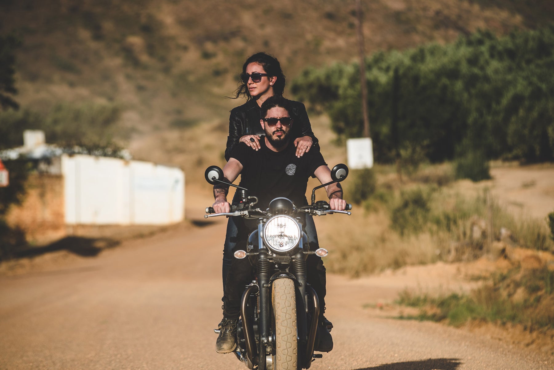 Jeff Campagna and Tania LaCaria, founders of Steeltown Garage Co. riding on a motorcycle in the South African countryside.