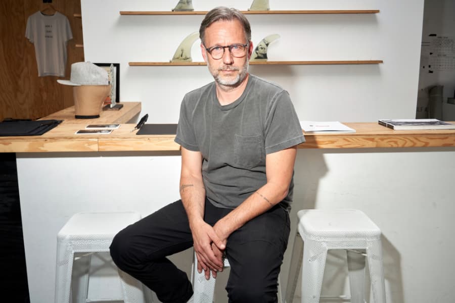 Alex Kemp, co-founder of Lone Wolfs, sits in front of a desk in his shop