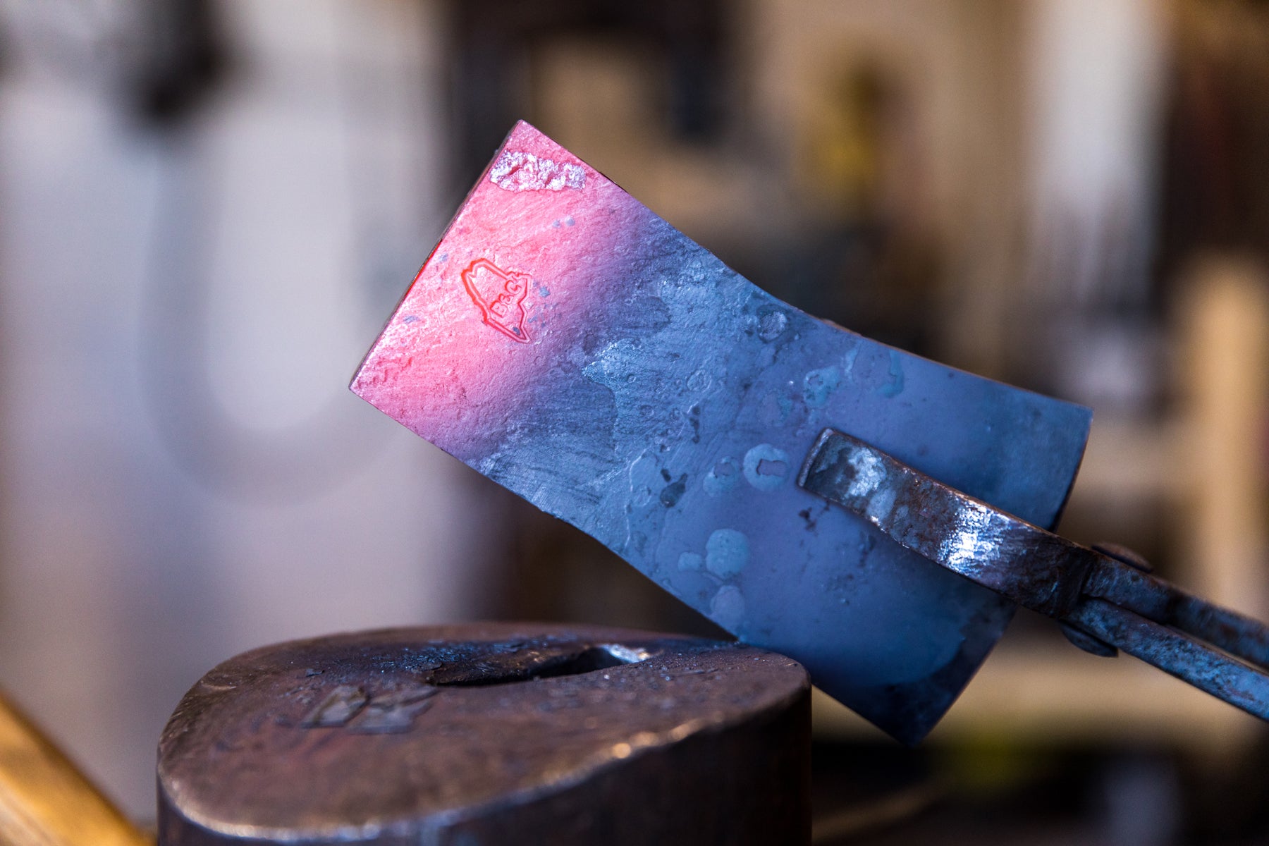 Detail of an axe-head glowing red and stamped with the Brant & Cochran logo.