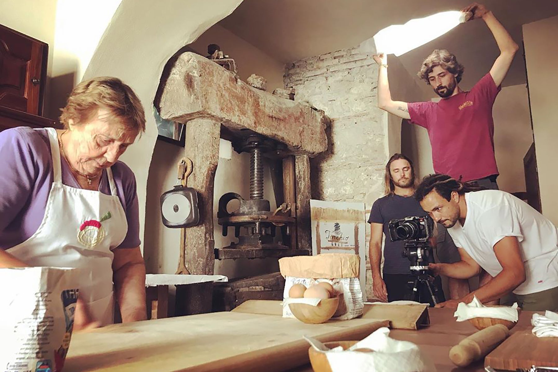 Nonna Nerina makes pasta while a camera crew sets up the shot