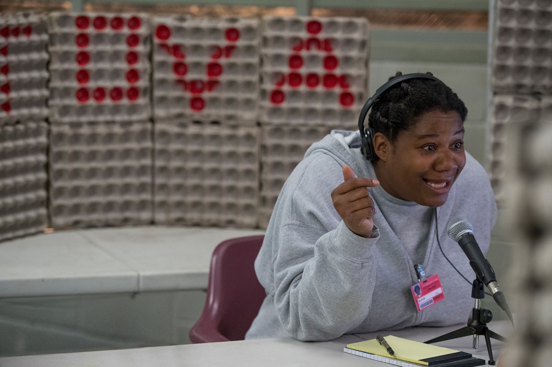 Cindy Hayes wears headphones and speaks into a microphone in an episode of Orange Is the New Black.