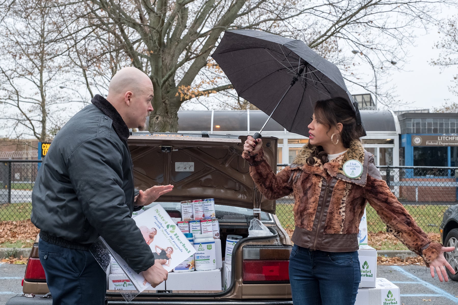 A guard confronts Aleida Diaz who is selling drink powder from the trunk of her car in an episode of Orange Is the New Black.