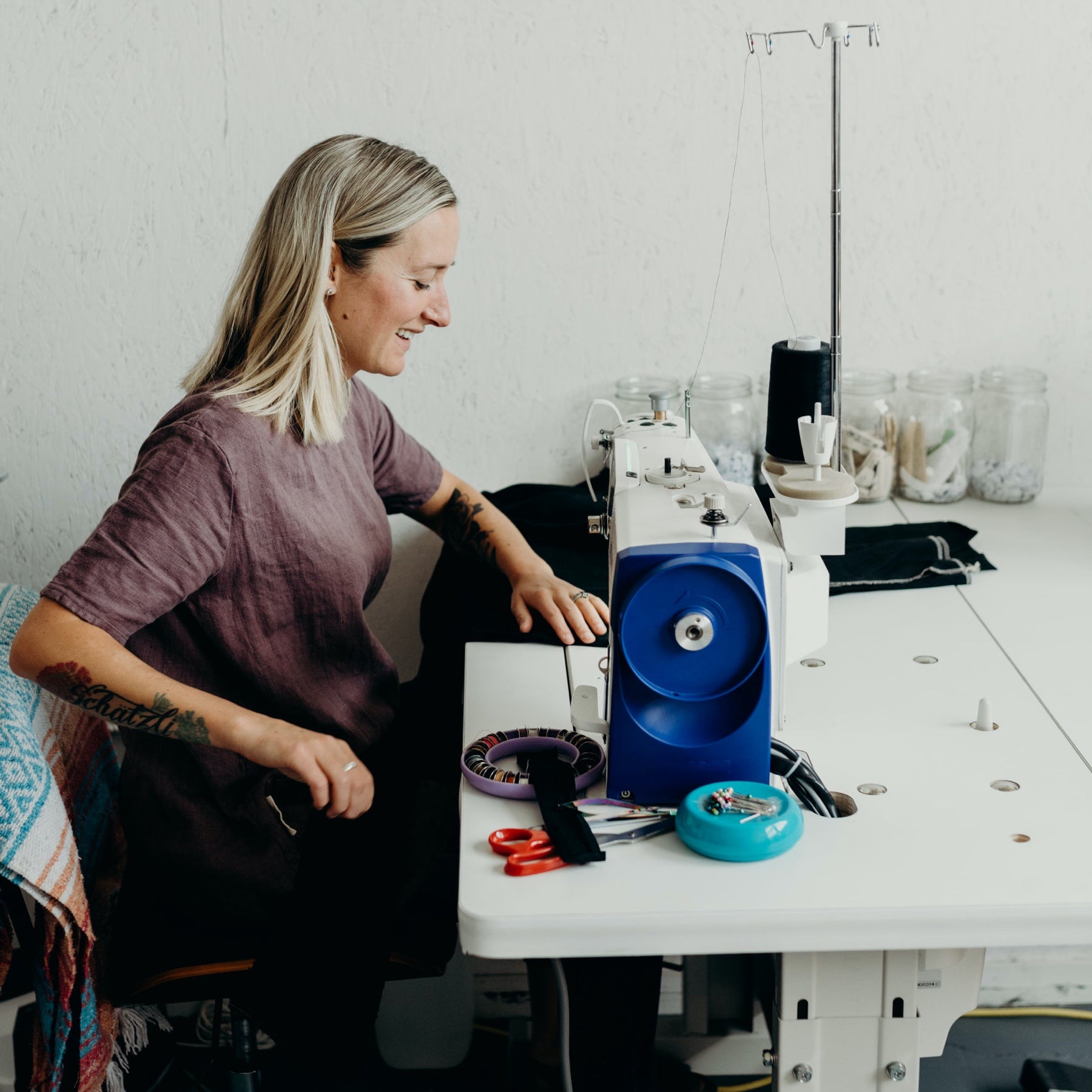 Portrait of Portland Apron Company founder Erika Kelly sitting at her sewing machine