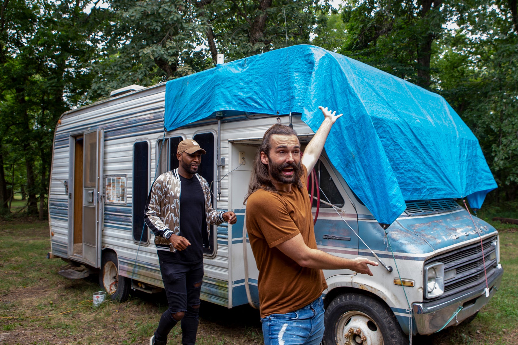 Jonathan gestures toward a camper van covered in a tarp while Karamo stands by in an episode of Queer Eye.
