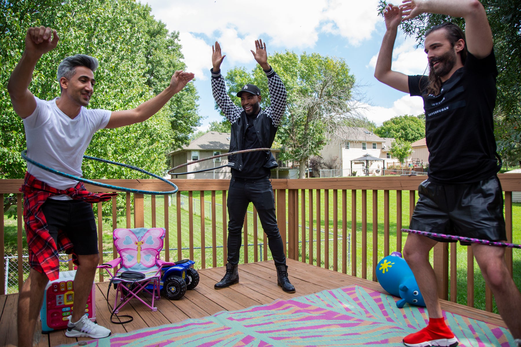 Tan, Karamo, and Jonathan use Hula-oops on a deck in an episode of Queer Eye.