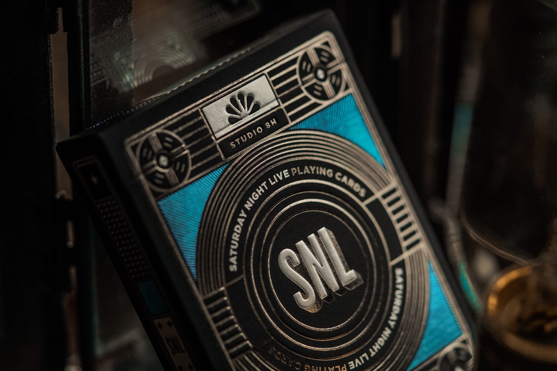 Close up photograph of a deck of custom designed Theory11 playing cards for Saturday Night Live. SNL is featured on the front of the card in large gold leaf letters. 