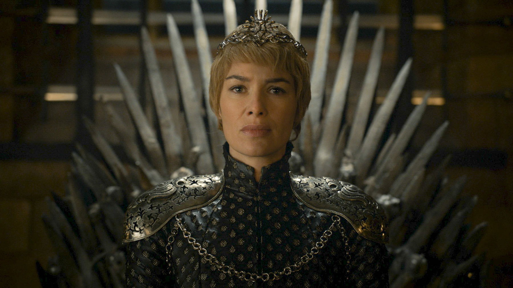Cersei Lannister sits on the Iron Throne in a crown.