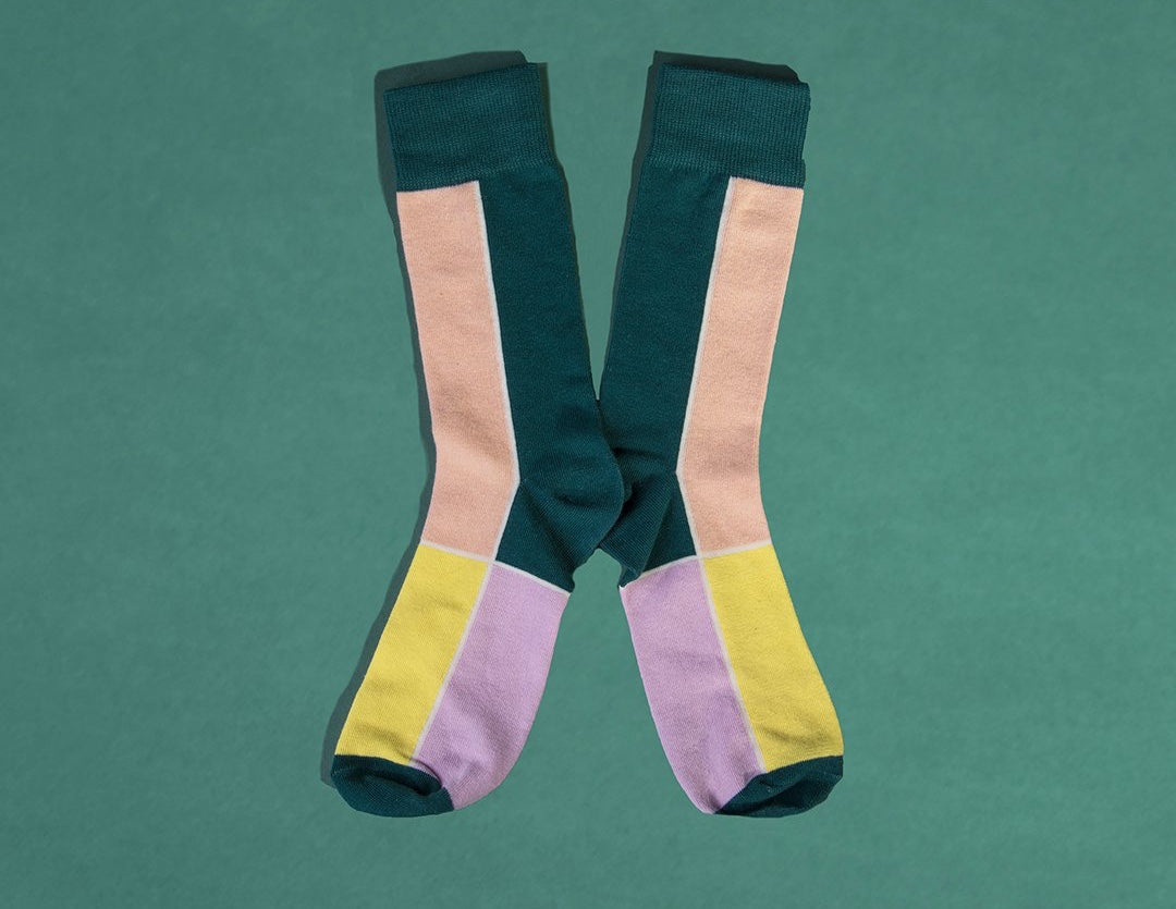 Green, white, yellow, and pink colorblock socks against a green background